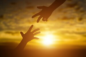 Silhouette of giving a help hand, hope and support each other over sunset