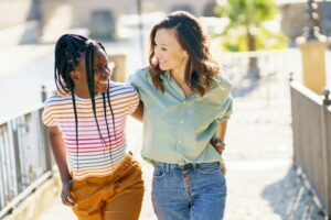 Two friends talking together on the street. Multiethnic women